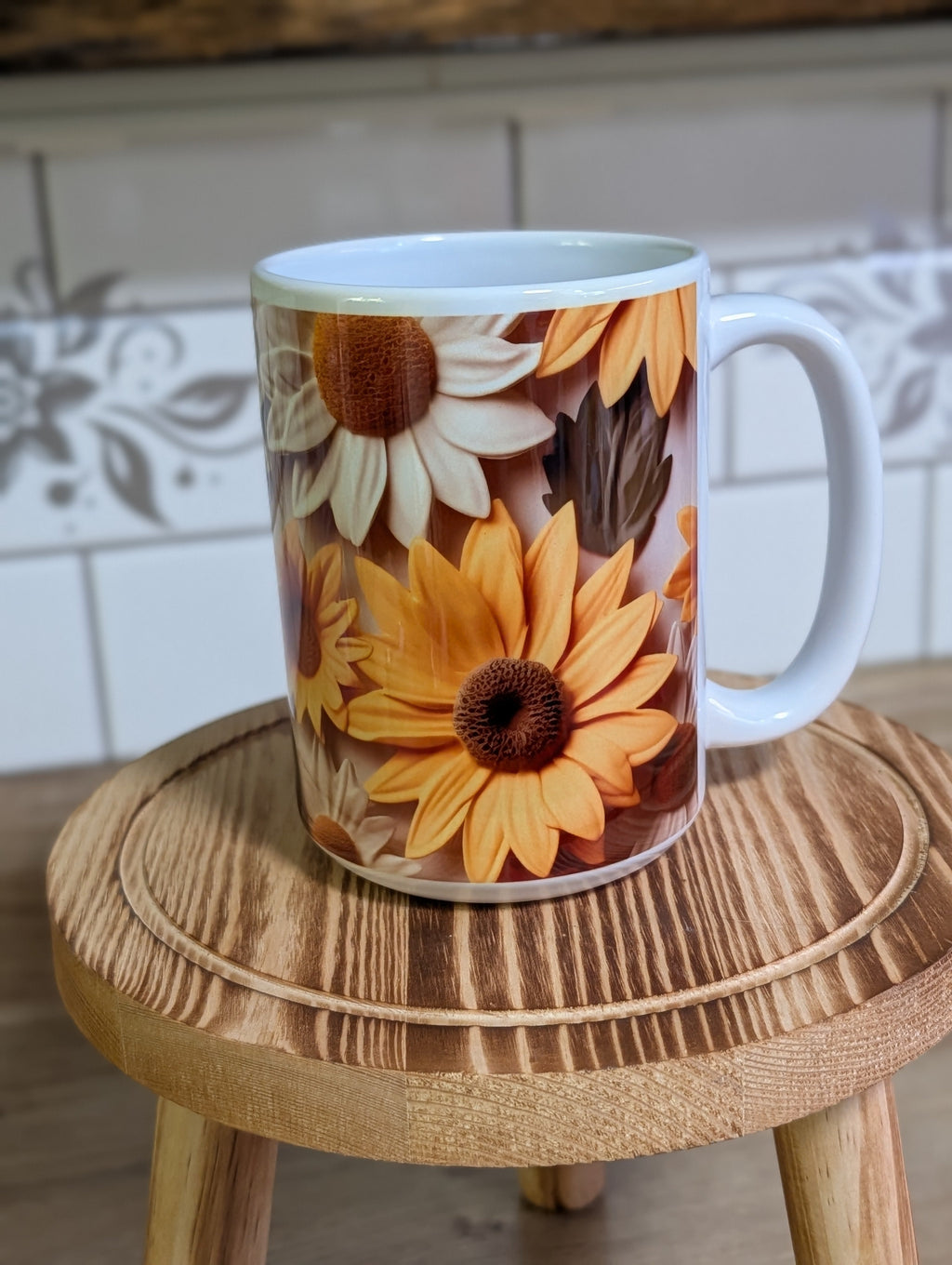 3D sunflower and daisy ceramic mug front view on wooden stool showing golden sunflower and white daisy design