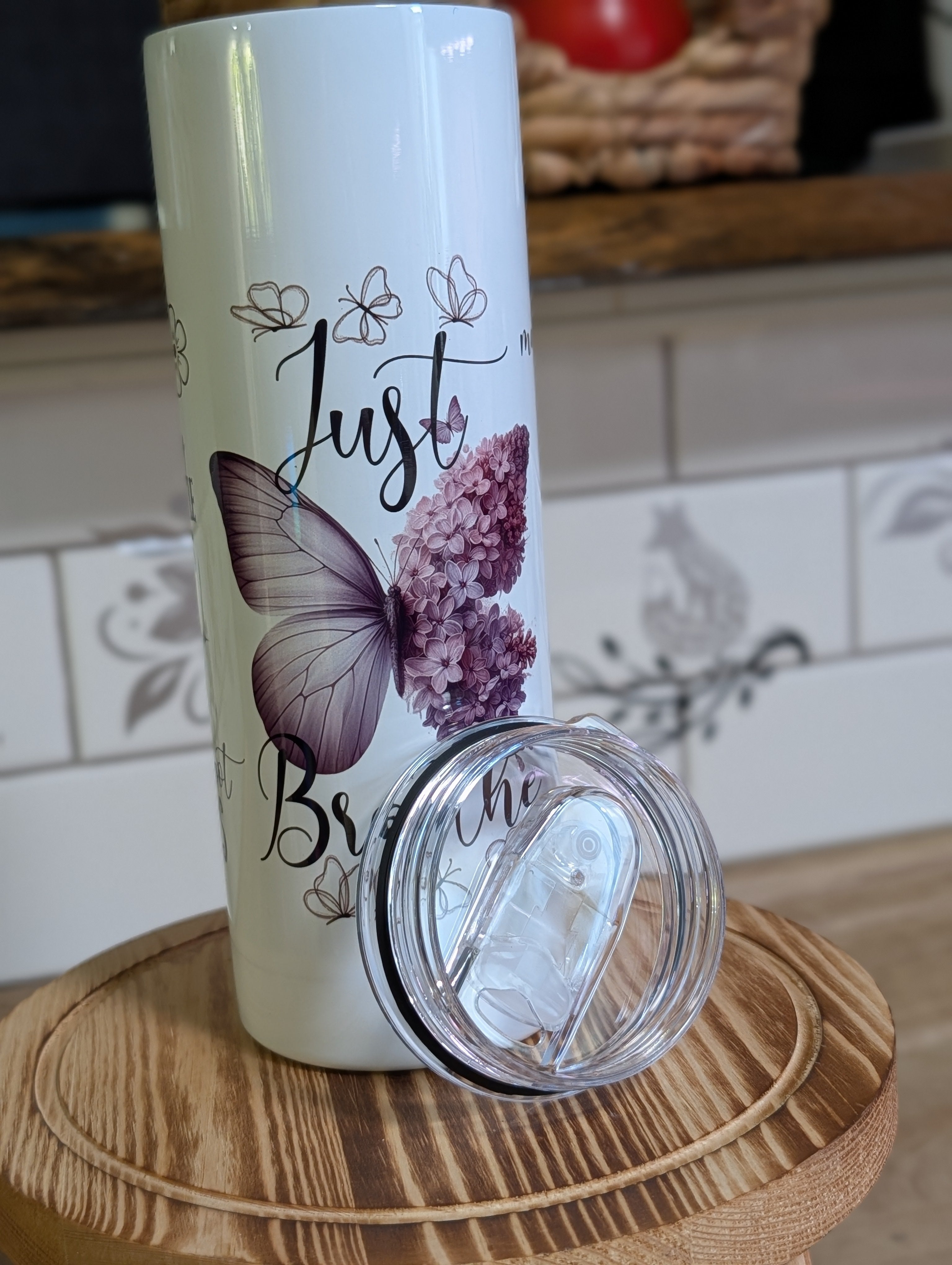 Just Breathe butterfly tumbler with lid off close up on wooden stool