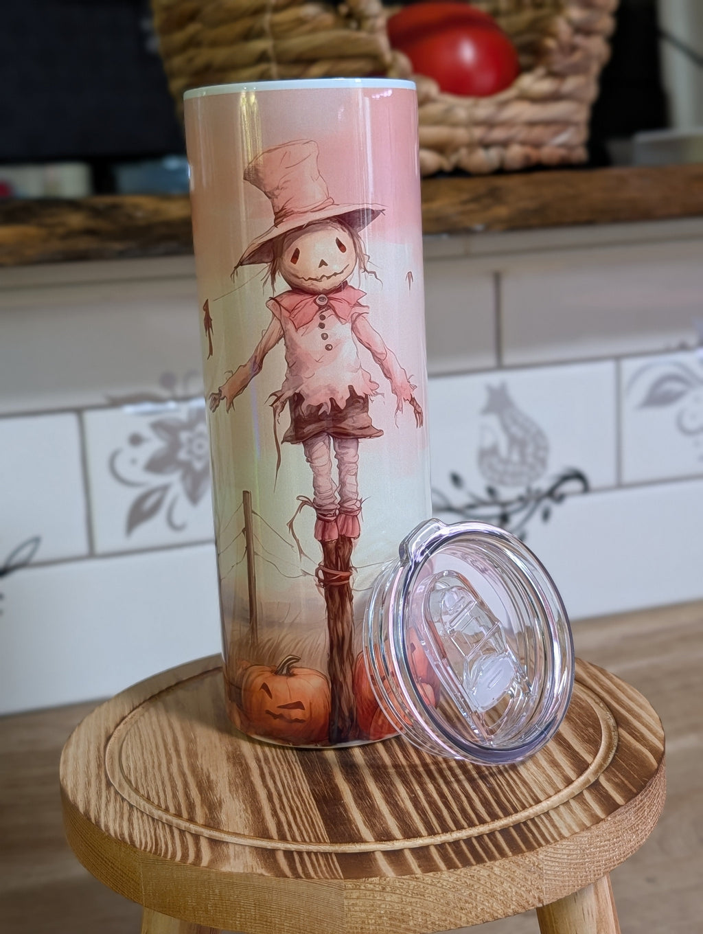 Watercolor scarecrow tumbler front view with lid off and straw on wooden stool