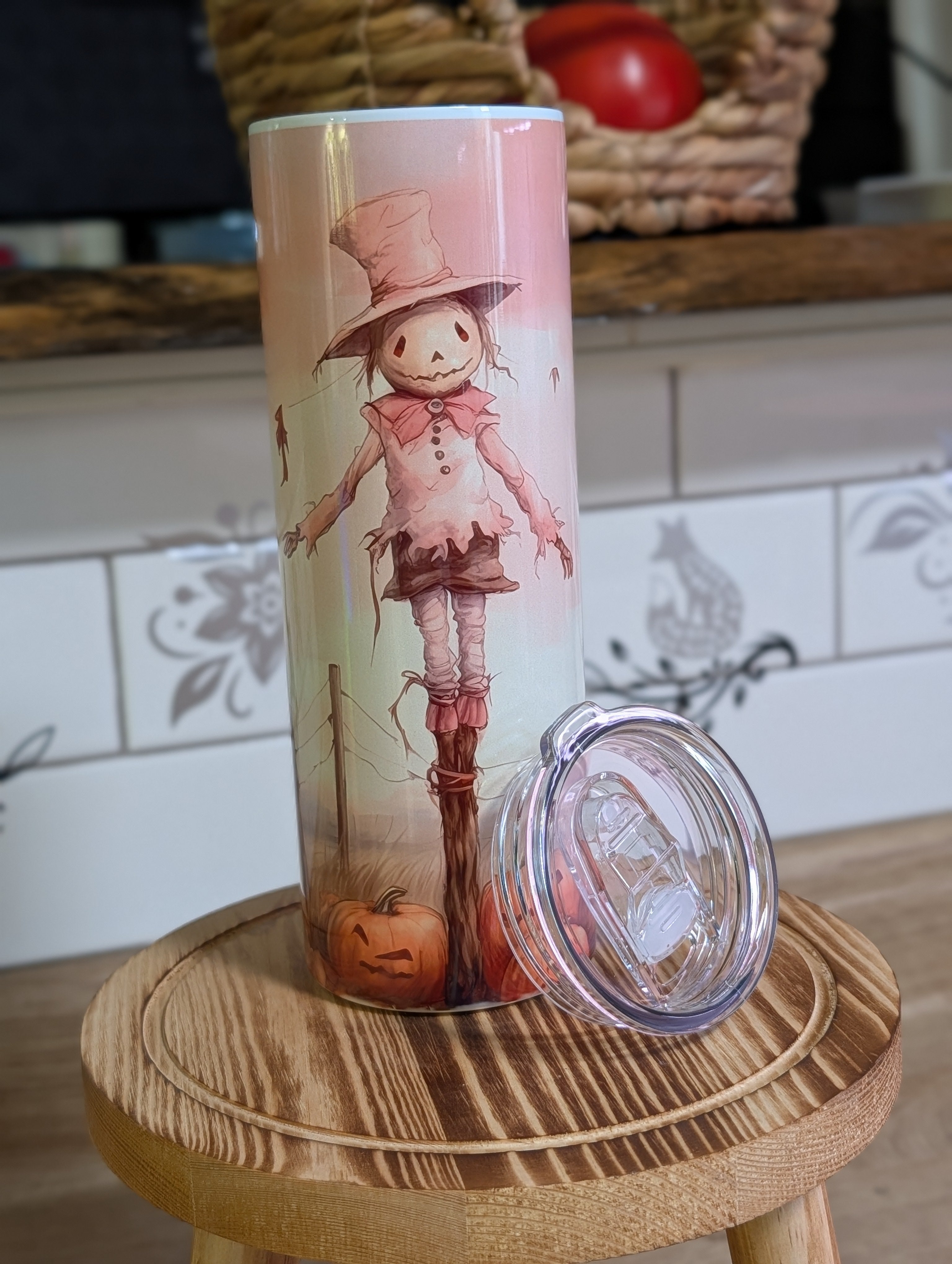 Watercolor scarecrow tumbler front view with lid off and straw on wooden stool