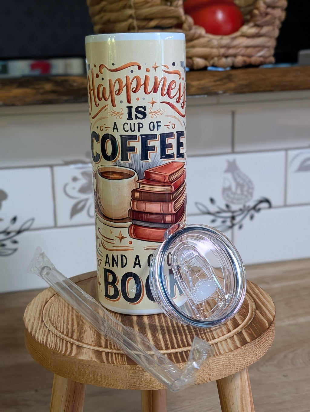 Happiness Is a Cup of Coffee and a Good Book tumbler with lid and straw on wooden stool