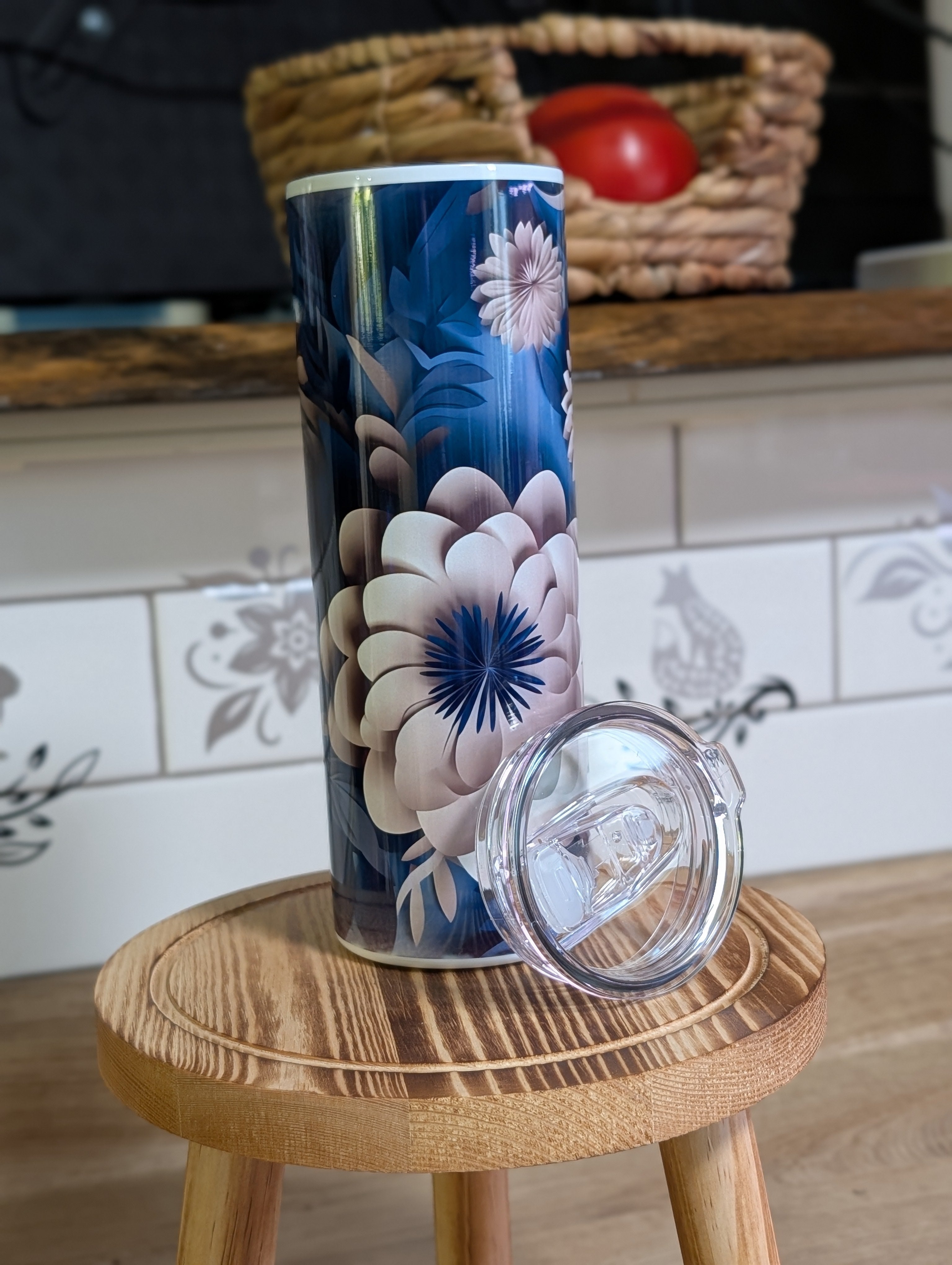 3D navy blue floral peony tumbler with lid and straw beside it on wooden stool
