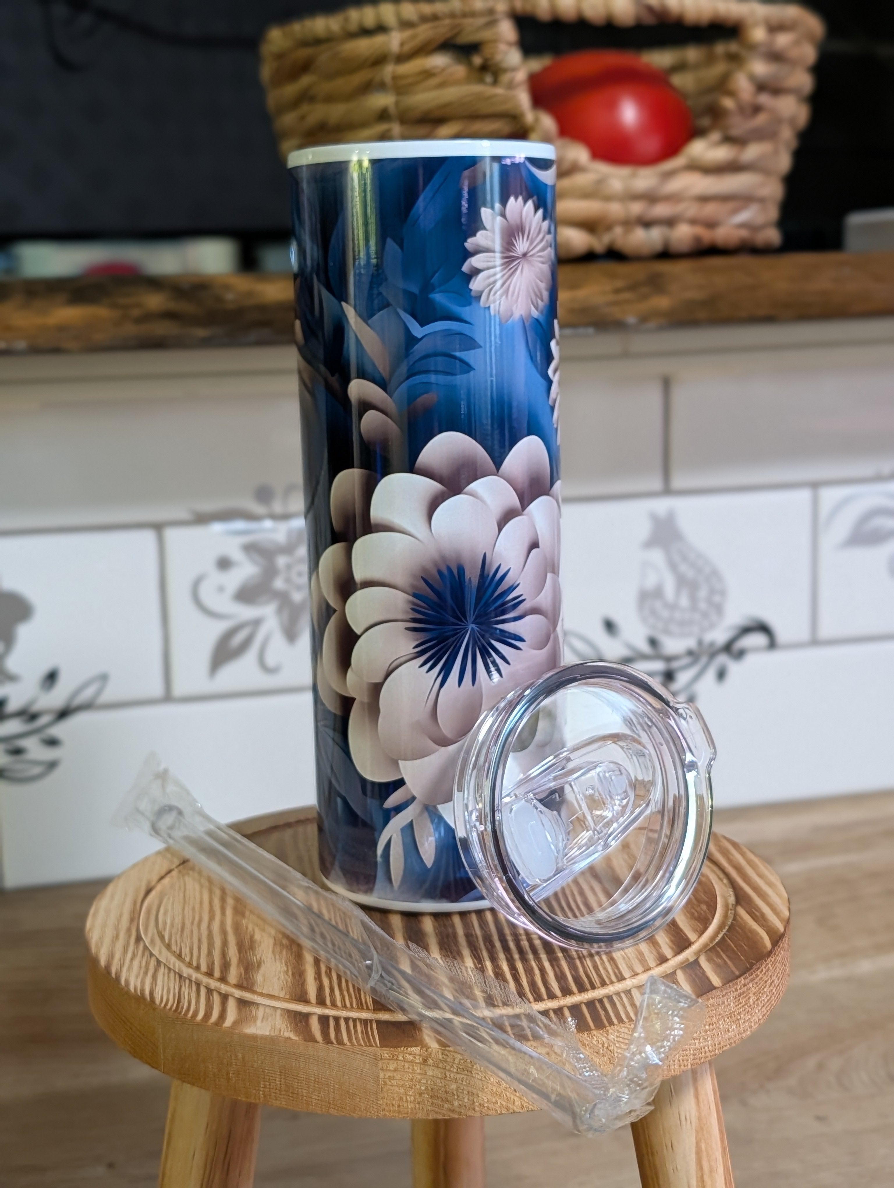 3D navy blue floral peony tumbler with lid off and straw on wooden stool