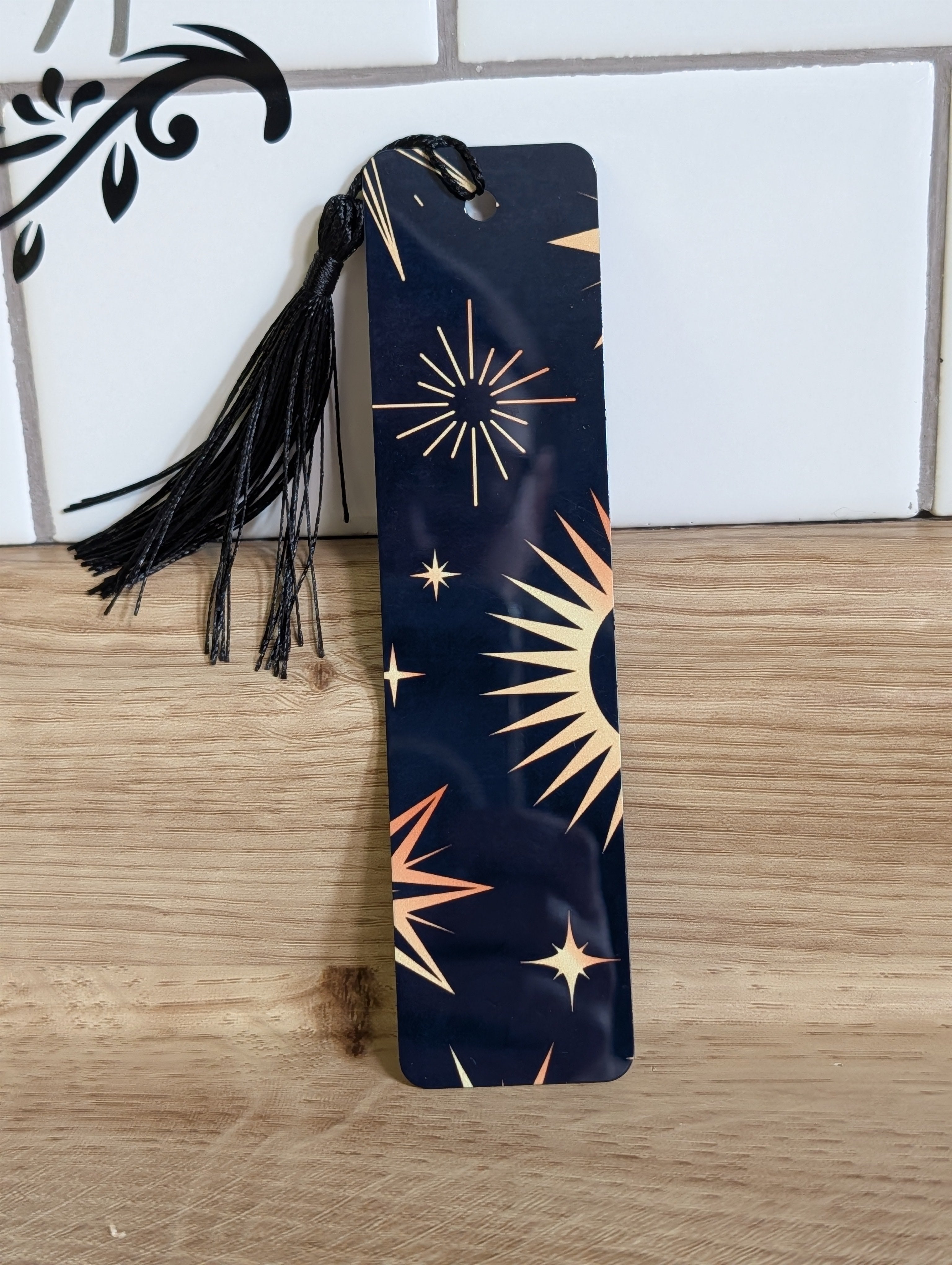 Celestial bookmark back - navy background with gold starburst and star designs with black tassel