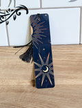 Celestial bookmark front - navy background with crescent moon, gold sunburst and stars with black tassel