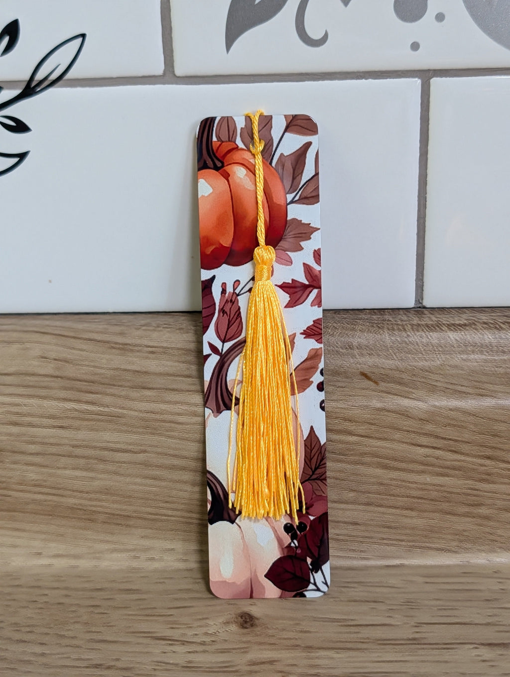 Pumpkin harvest bookmark front - white background with orange pumpkin and dark autumn leaves with yellow tassel