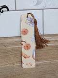 Cozy autumn bookmark front - cream background with dried oranges, croissant, cherries and gift box with bronze tassel