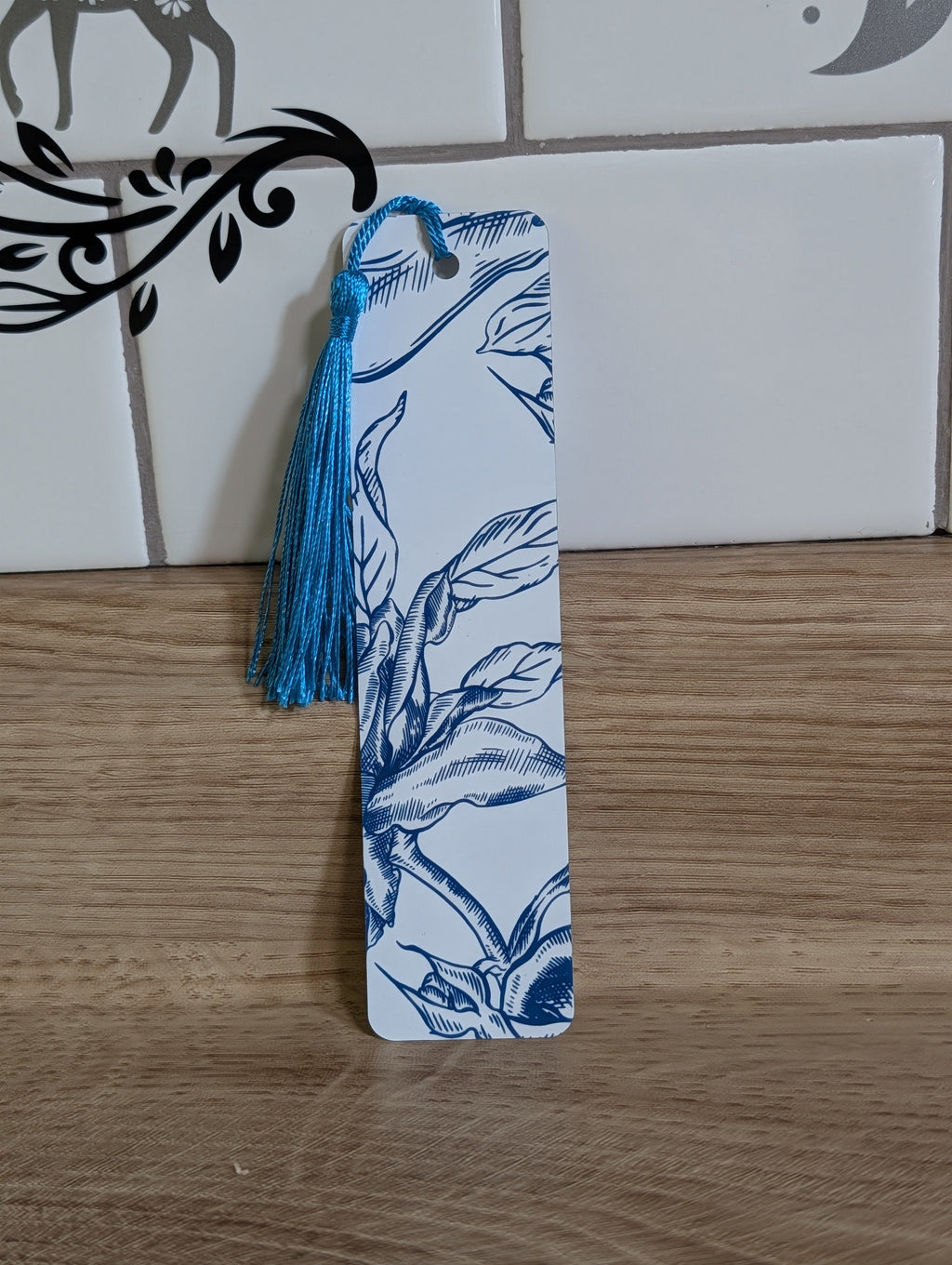 Blue rose etching bookmark back - white background with navy botanical leaves and branch illustration with blue tassel