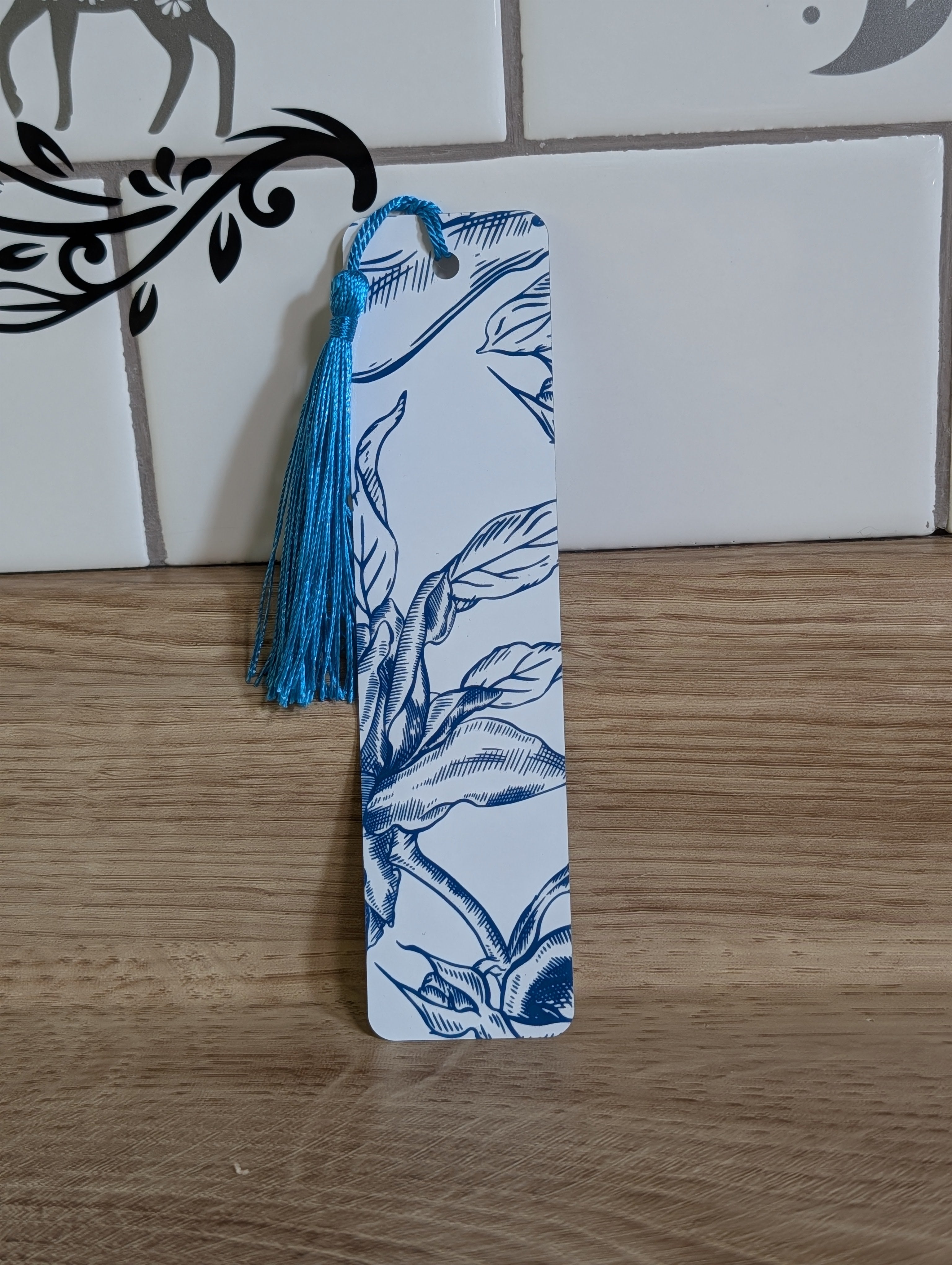 Blue rose etching bookmark back - white background with navy botanical leaves and branch illustration with blue tassel