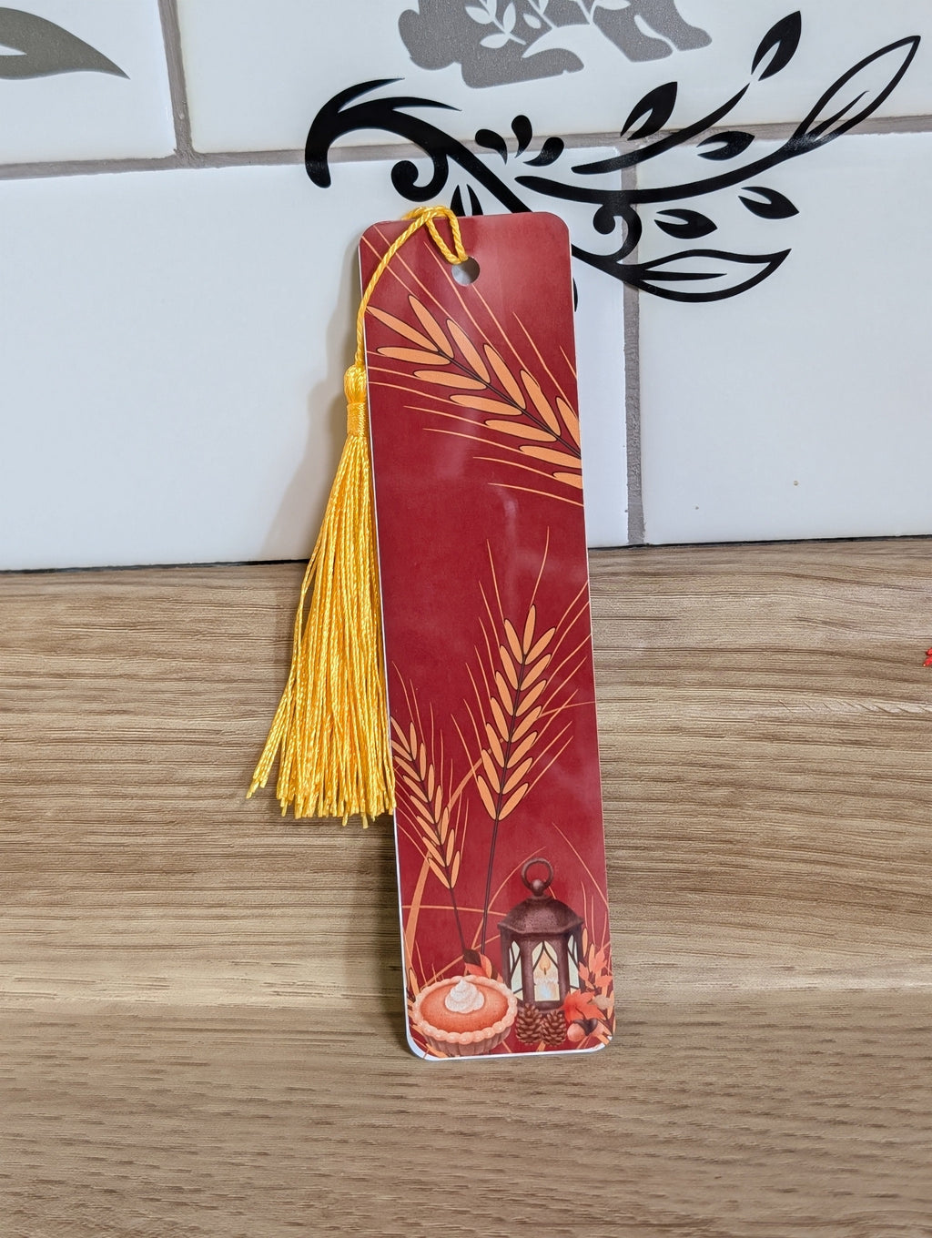 Thanksgiving wheat bookmark front - crimson background with golden wheat, lantern, and pumpkin pie with gold tassel