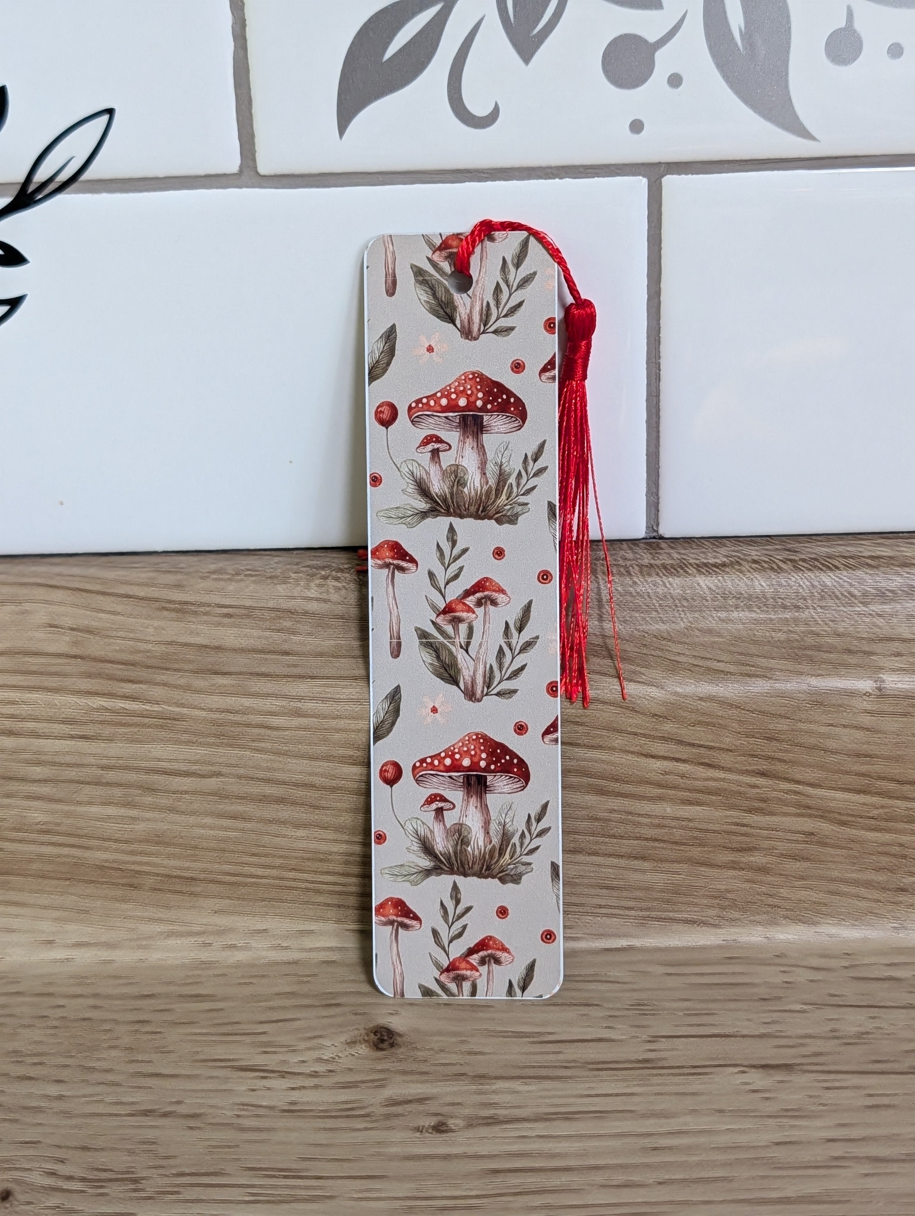 Mushroom bookmark back - neutral background with red toadstool mushrooms and botanical leaves with red tassel