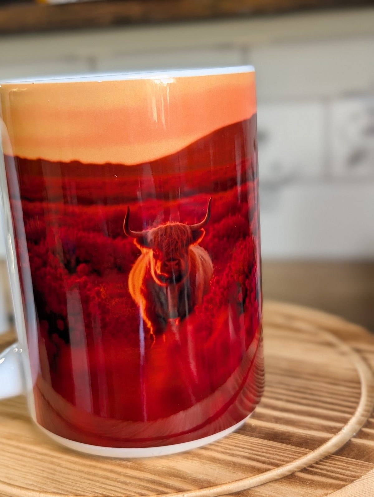 Highland cow sunset mug standalone on wooden surface showing full wrap crimson field design