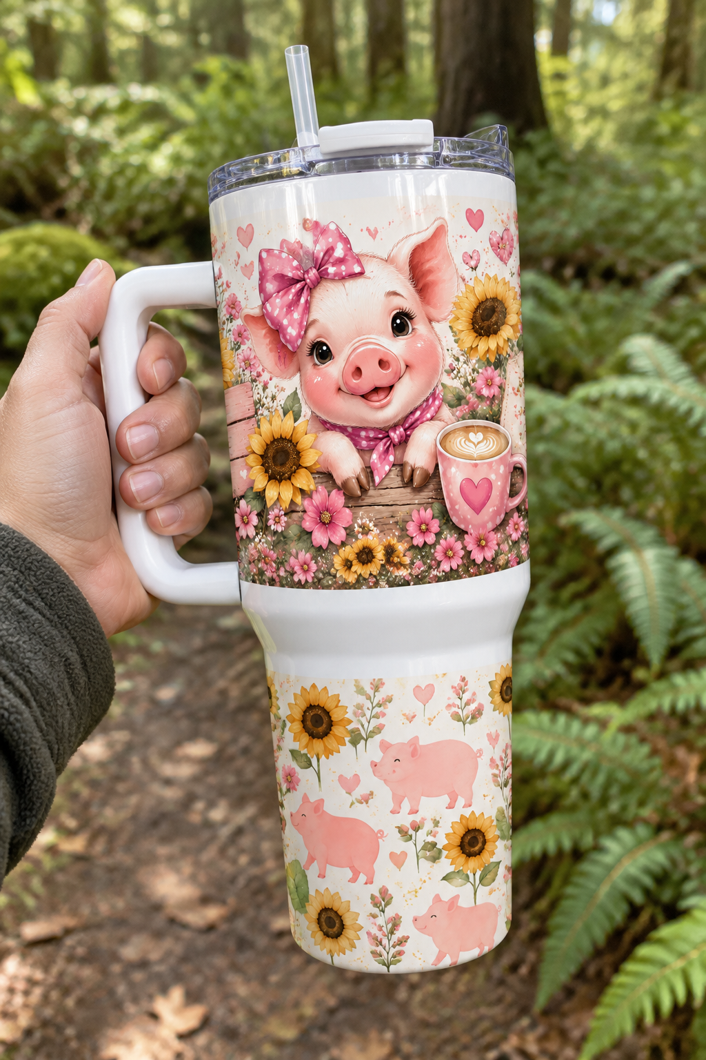 Hand holding a pink pig and sunflower 40oz handled tumbler on a woodland walk