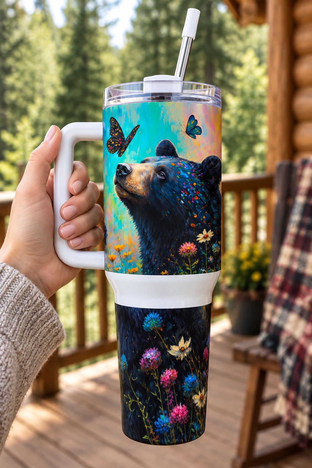Butterfly Bear 40oz tumbler held by handle on cabin porch